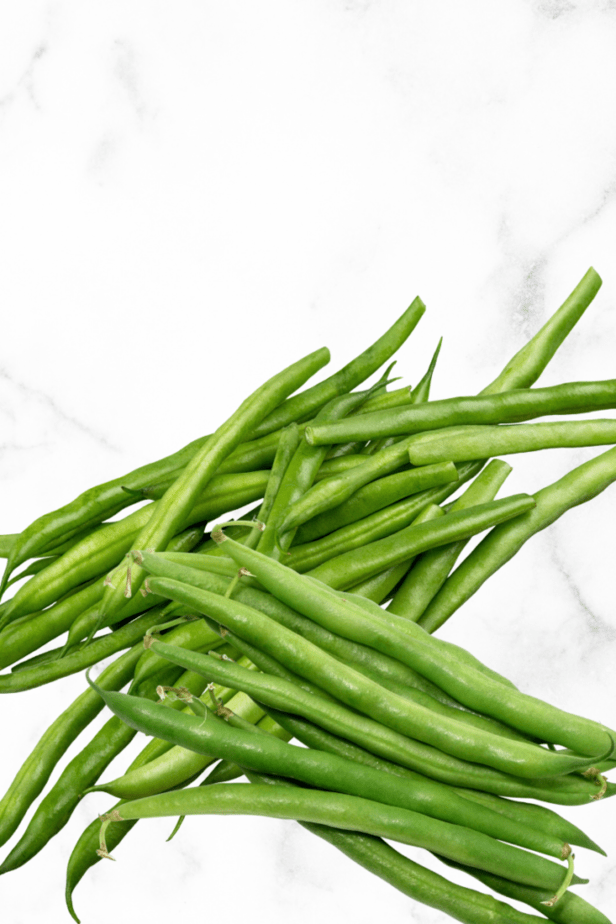 a bunch of green beans on a white marble counter